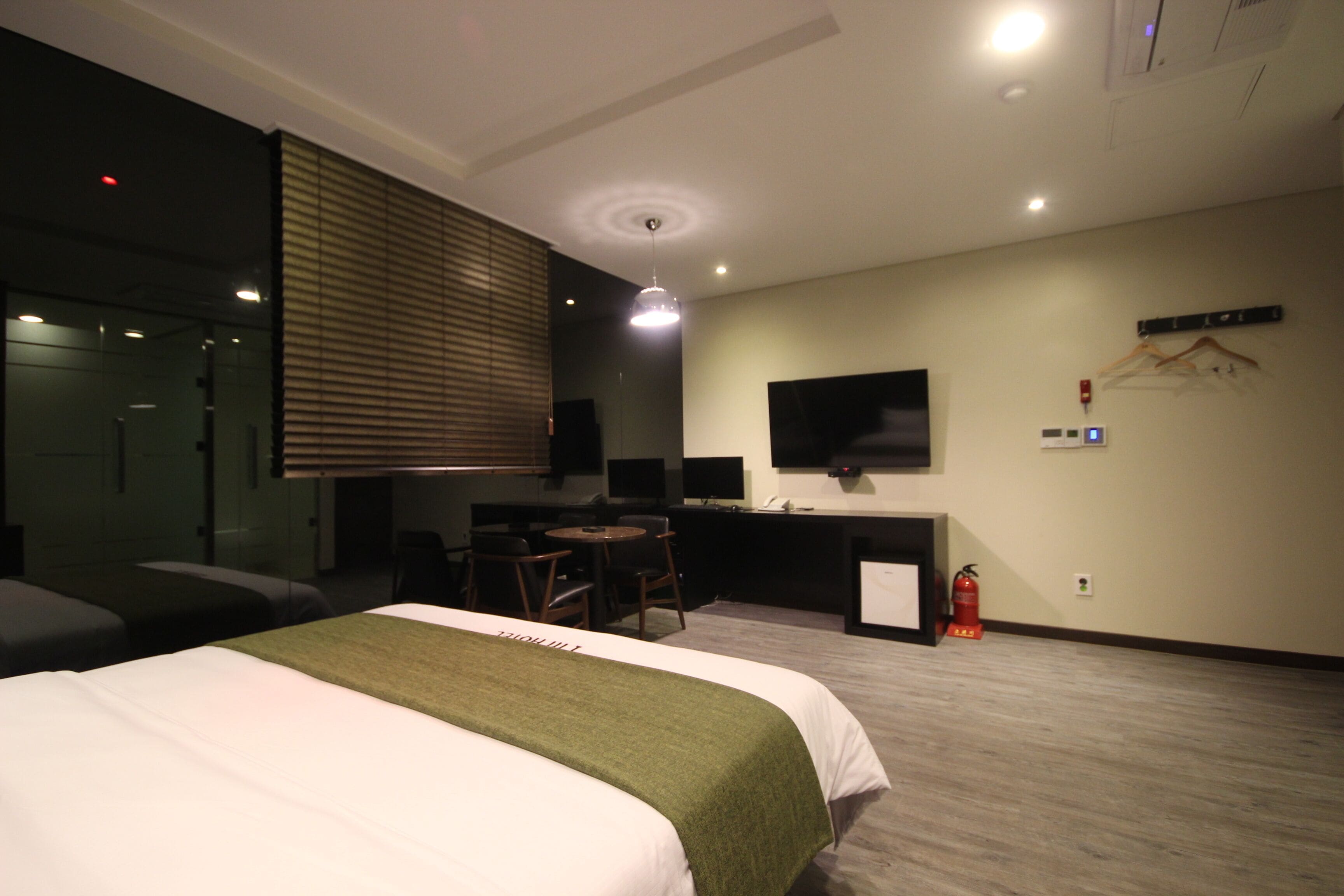 Une chambre d’hôtel équipée d’un lit, d’un bureau, d’une chaise, d’une télévision et d’un extincteur.