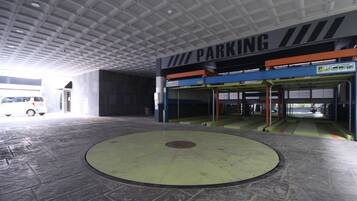 Interior de un aparcamiento con una zona circular central, varios niveles de estacionamiento y un indicador de disponibilidad de plazas.