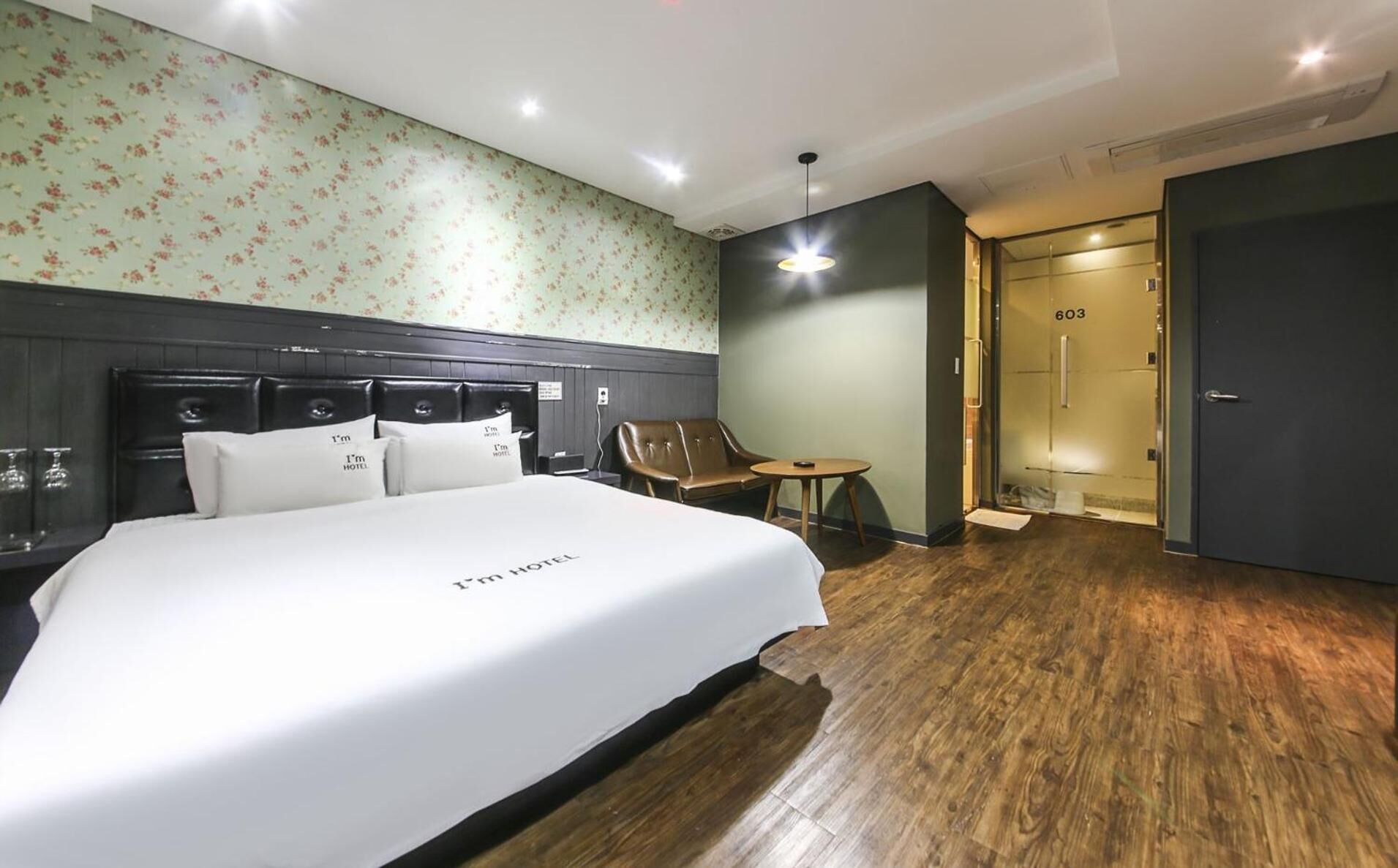 Una habitación de hotel con una cama grande, piso de madera, un sofá y una mesita.
