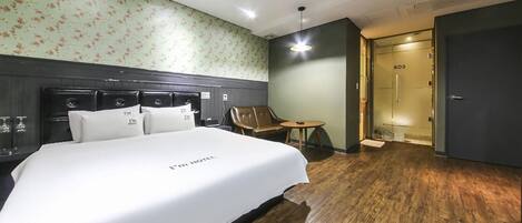 Una habitación de hotel con una cama grande, piso de madera, un sofá y una mesita.