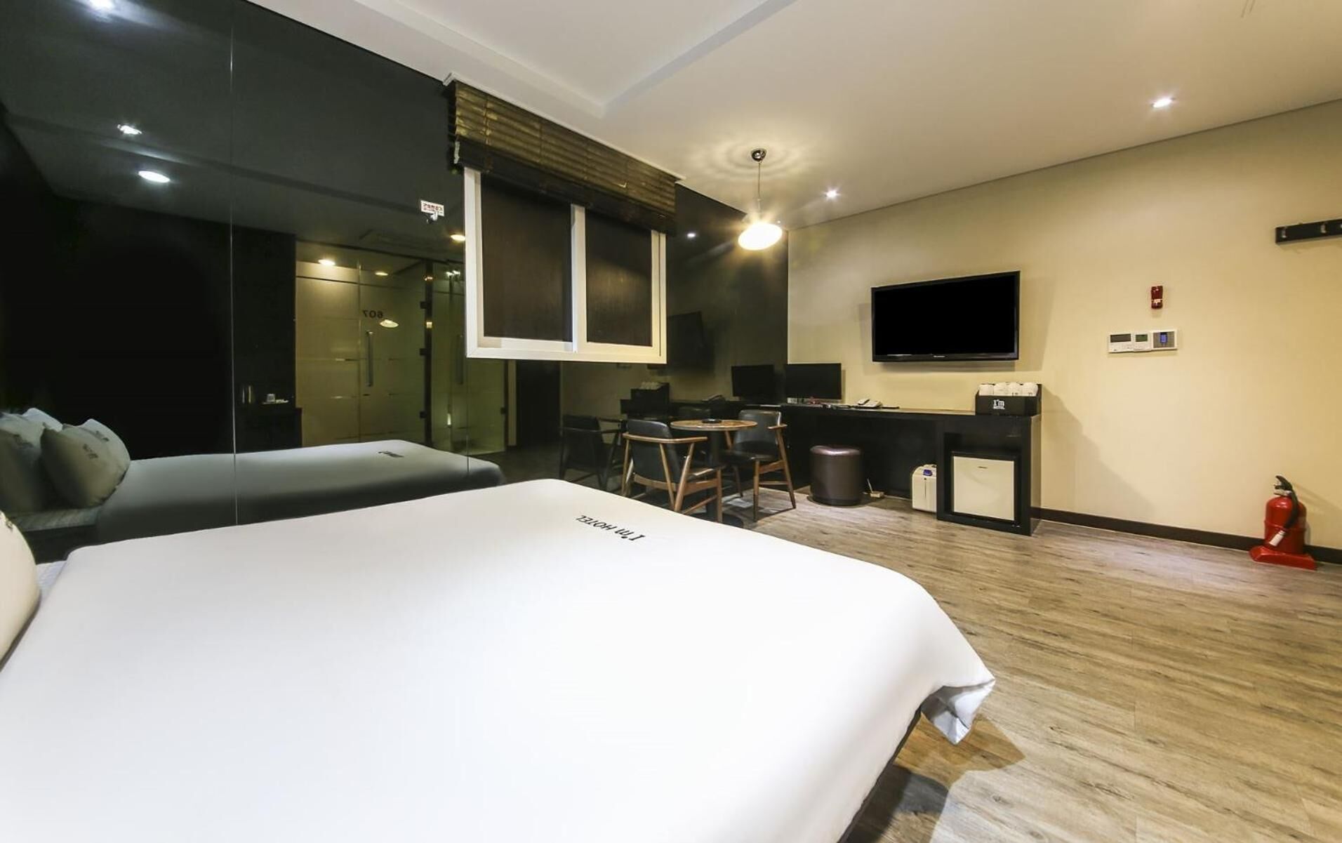 Habitación de hotel con una cama grande, un escritorio con una computadora, un televisor y una pequeña zona de estar.