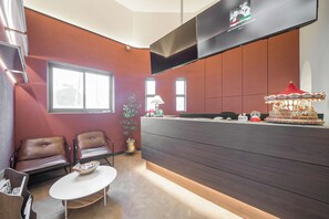Un espace d’accueil au design moderne, comprenant un comptoir de réception en bois foncé, des fauteuils en cuir, une petite table avec un récipient et un carrousel décoratif.