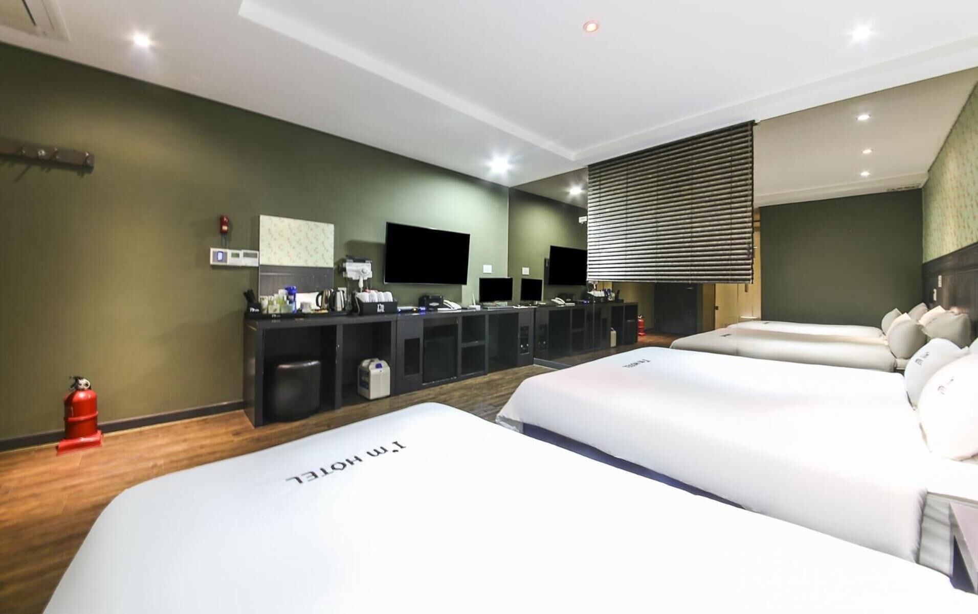 Et hotelværelse med to senge, et skrivebord med computer, et fjernsyn og et minibar.