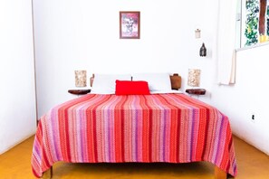 A bed with a striped bedspread, a red pillow, and two bedside tables with decorative items.
