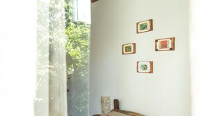 A room with a bed, a window with a view of greenery, and four framed pictures on the wall. - Pousada Jardim da Nova Era (Alto Paraíso de Goiás)