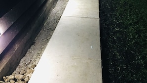 A concrete pathway adjacent to a dark building with illuminated windows. - 2 Bedroom Kona Coffee Farm with Ocean Views in Holualoa (Holualoa)