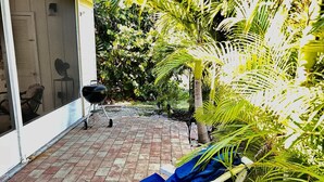 A patio with a grill, a chair, and lush greenery. - Steps to the ocean and inlet (Hutchinson Island)