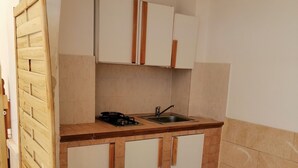 Eine kleine Küche mit weißen Schränken, einer Holz Arbeitsplatte und einer gefliesten Spritzschutzwand.