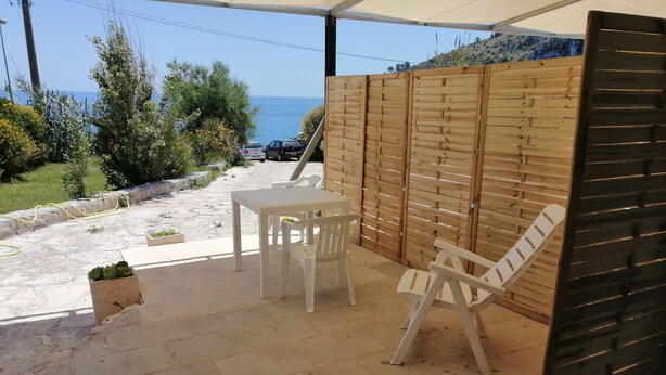 Eine Terrasse mit Tisch und Stühlen, einem Holzzaun und Blick aufs Meer.