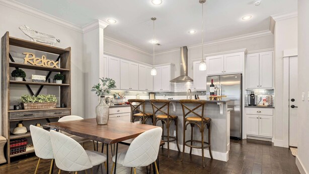 A modern kitchen with white cabinets, a wooden dining table, and bar stools. - Wright Place - Walk to Downtown - 0.5 mi to UofA (Fayetteville)