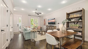 A dining area with a wooden table, white chairs, and a ceiling fan. - Wright Place - Walk to Downtown - 0.5 mi to UofA (Fayetteville)