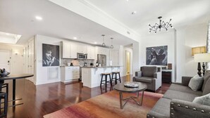 Ein geräumiger Wohnbereich mit einer großen Couch, einem Couchtisch und einer Küche im Hintergrund.