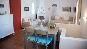 A dining area with a table, chairs, and a fireplace. There is a red door and a white cabinet in the room.