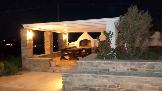An outdoor patio area with a stone wall, a barbecue grill, and a seating area.