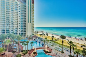 A high-rise hotel with a pool area, beach access, and a view of the ocean.