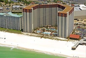 A high-rise hotel with multiple floors, a beachside location, and a pool area.