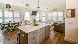 Una cocina amplia con una isla grande, armarios de madera e iluminación colgante.