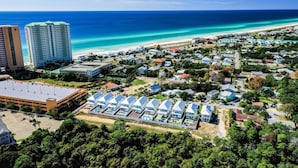 Zona turística costera con propiedades frente a la playa, un aparcamiento y edificios de gran altura.