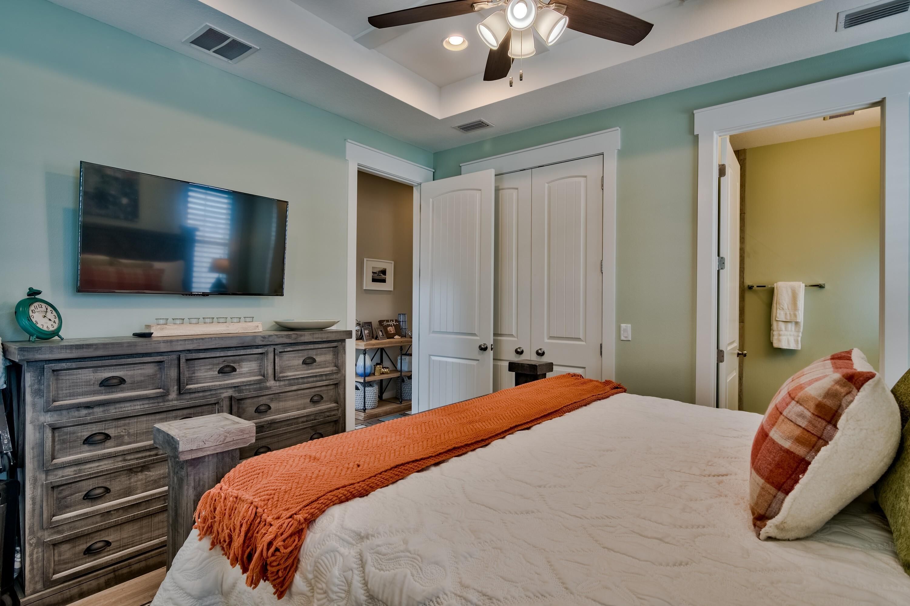 A bedroom with a bed, dresser, TV, and closet.