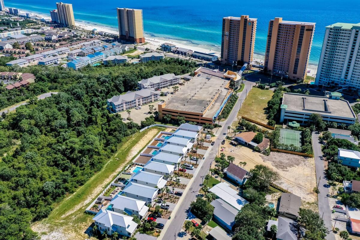 Vista aérea de una zona costera con edificios altos, un estacionamiento y una playa.