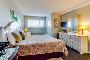 A bedroom with a large bed, a dresser, a vanity with a mirror, and a television on the wall. - The Summit by Forehand Rentals (Panama City Beach)