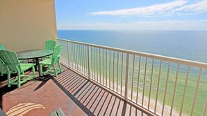 A balcony with a table and chairs, overlooking the sea.