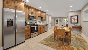 Una cocina moderna con electrodomésticos de acero inoxidable, armarios de madera y un comedor con mesa y sillas.