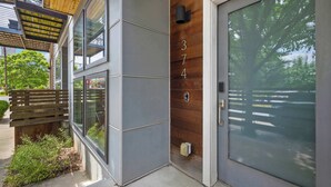 Un edificio moderno con un gran puerta de vidrio, fachada de madera y el número '3749' en la pared.