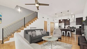Una sala de estar moderna con un sofá gris, una mesa de centro de vidrio y una escalera con escalones de madera.