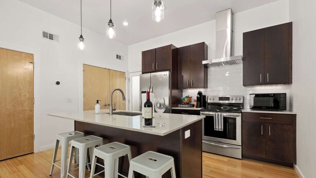 Una cocina moderna con una isla central, electrodomésticos de acero inoxidable y armarios de madera oscura.