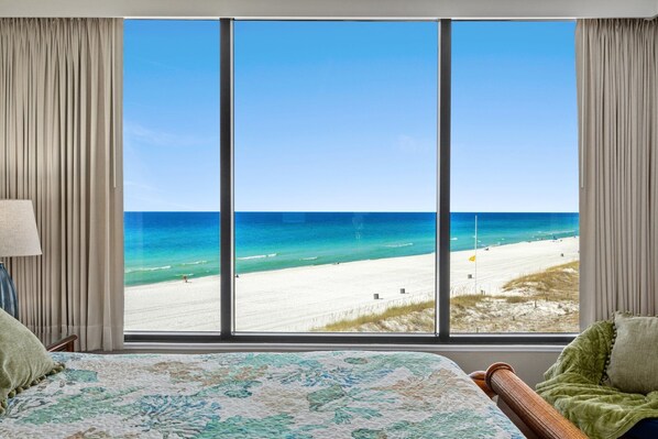 Ein Hotelzimmer mit großem Fenster und Blick auf den Strand.