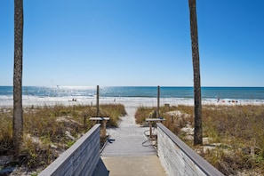A wooden boardwalk leading to a beach with clear skies.