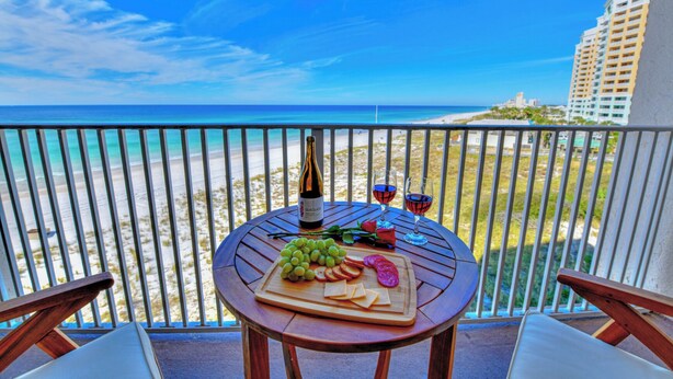 Varanda com mesa posta para refeição, com vista para a praia e oceano.
