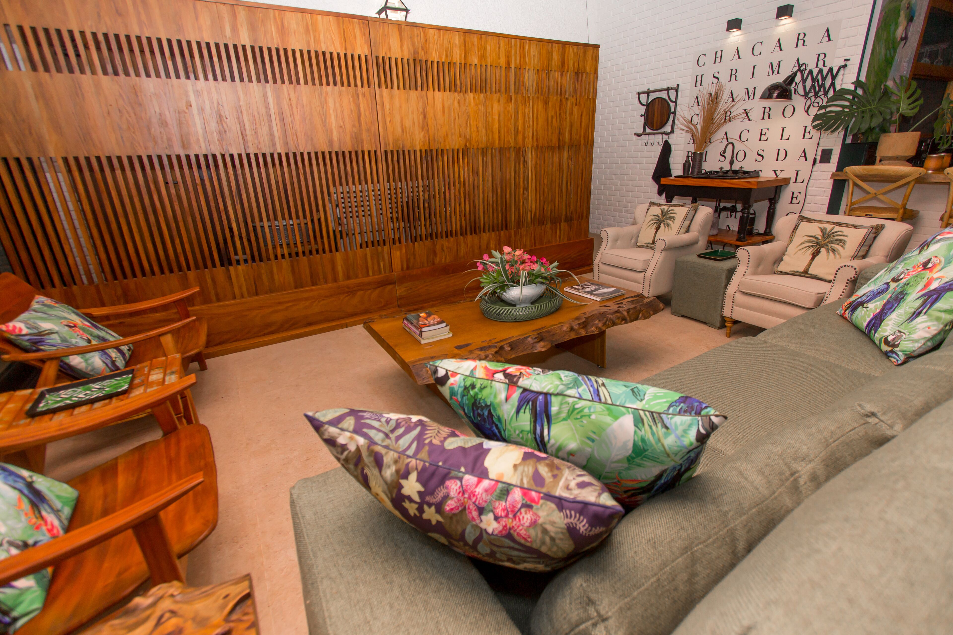 A living room with a wooden partition, a sofa with floral cushions, and a coffee table with decorative items.