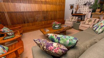 A living room with a wooden partition, a sofa with floral cushions, and a coffee table with decorative items.