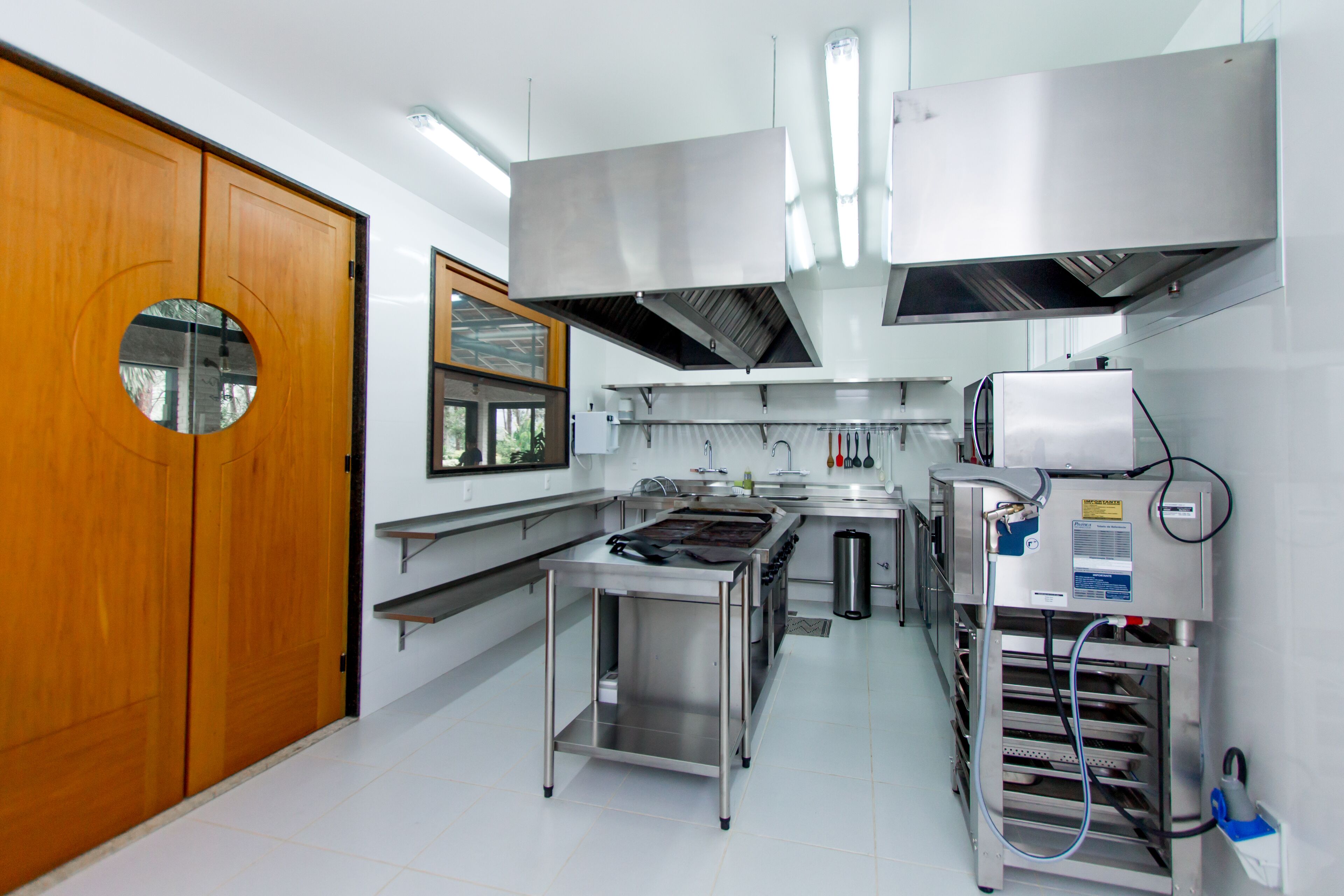 A modern kitchen with stainless steel appliances, a wooden door, and a window.