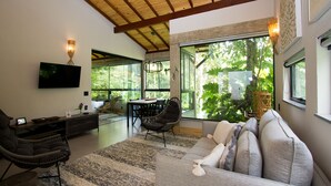 A modern living room with a large window, a flat-screen TV, a sofa, and a dining area. - Pousada Chácara Aracê (Petrópolis)