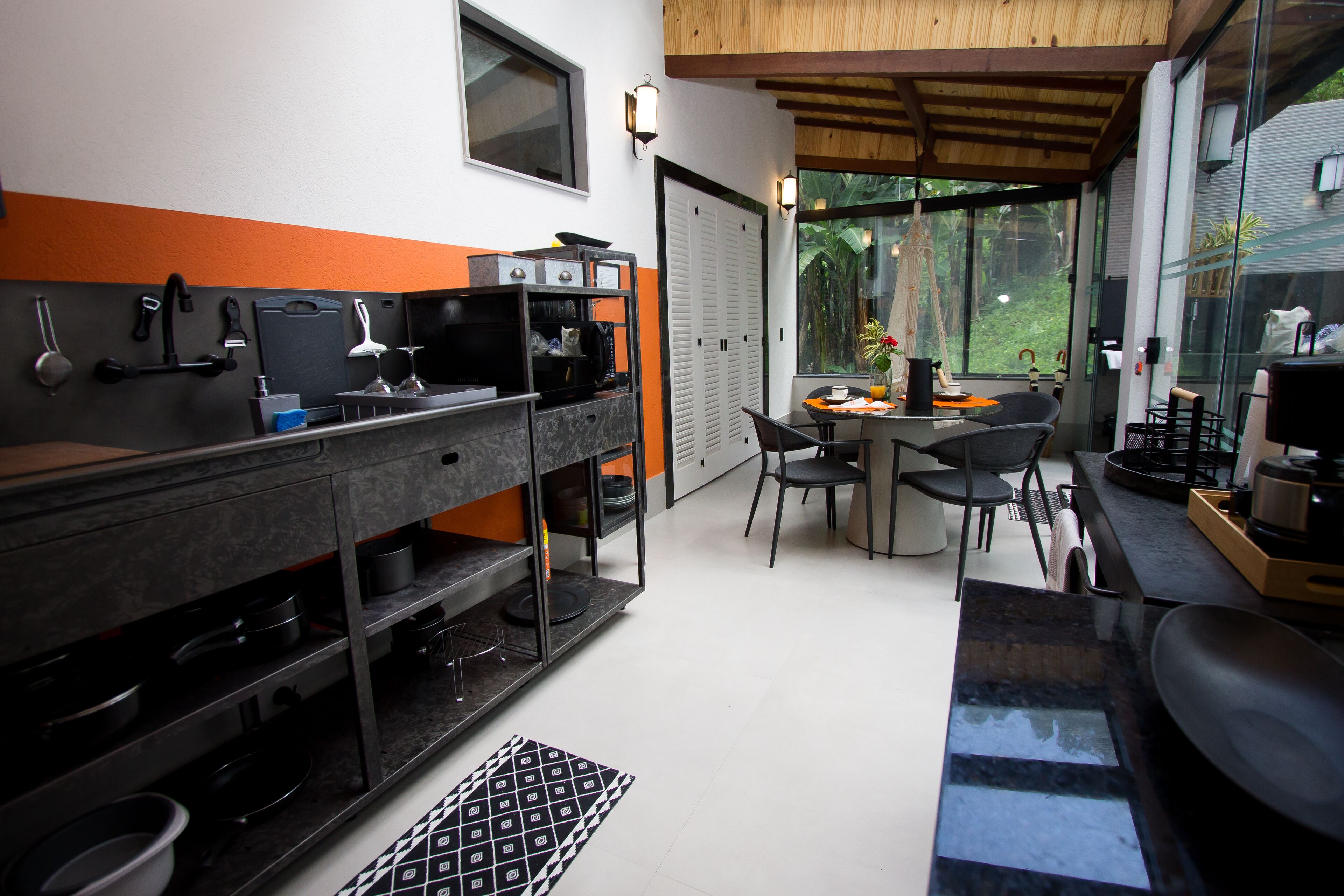 A modern kitchen with a dining area, featuring a built-in oven, microwave, and various kitchen utensils.
