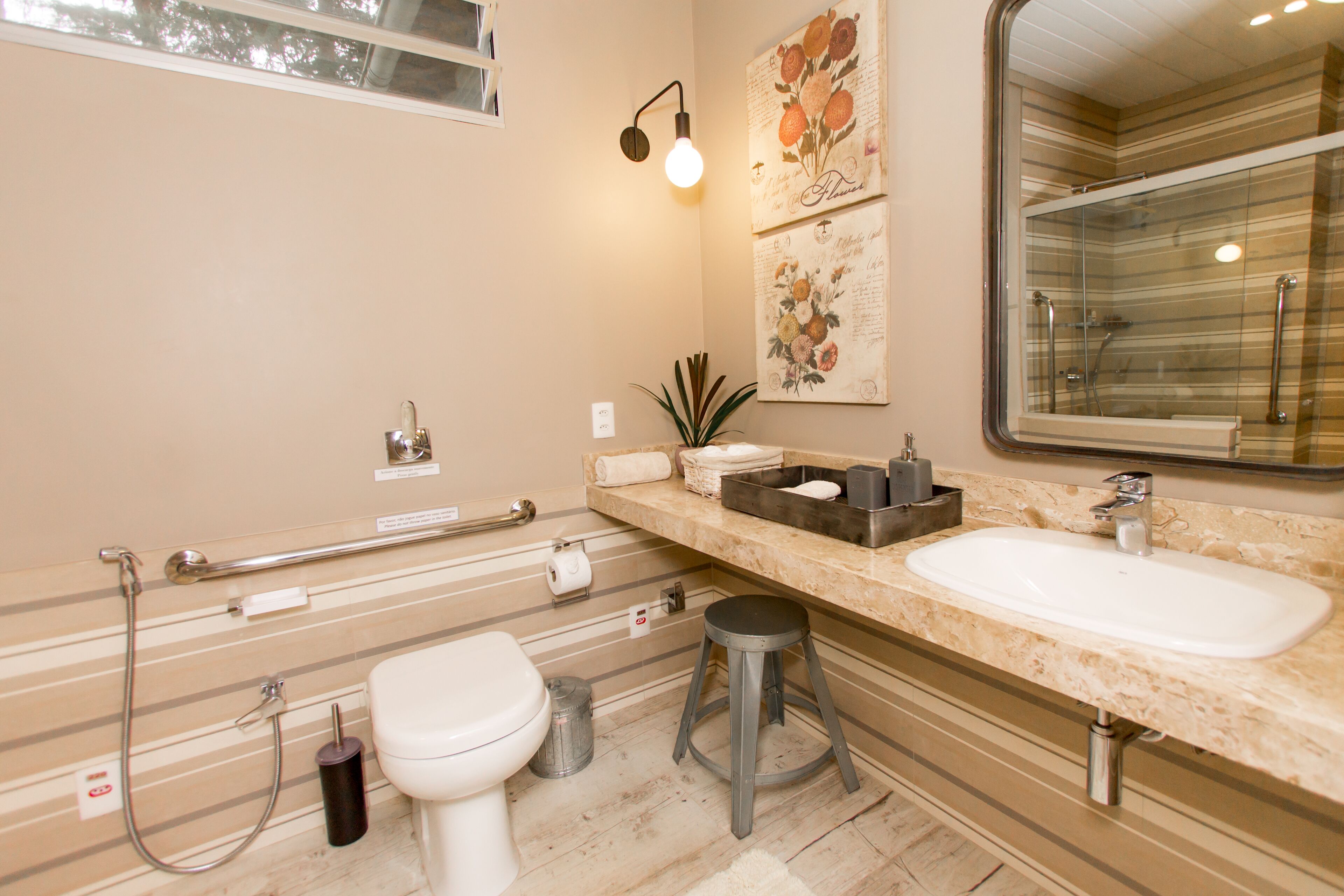 Un baño moderno con un espejo grande, un lavamanos, un inodoro y una zona de ducha.