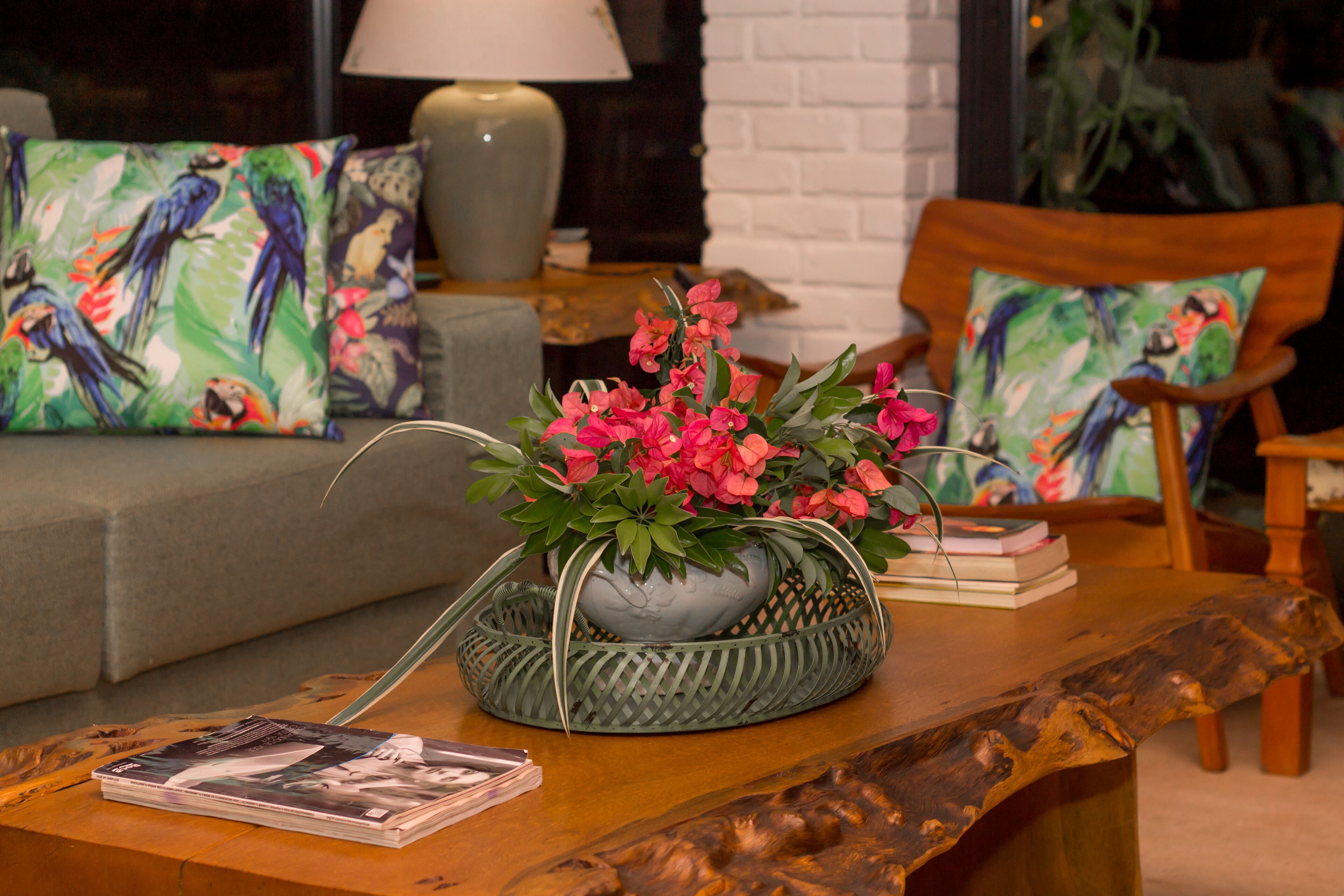 A living room with a wooden coffee table, a grey sofa, and two armchairs. There is a decorative bowl with flowers on the coffee table.