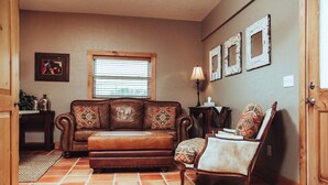 A cozy living room with a brown leather sofa, a patterned armchair, and a small side table with a lamp. - 1- Bedroom 1- Bathroom Ranch Guest house. (Ellensburg)