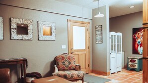 A hallway with a patterned armchair, a wooden bench, a door, and a cabinet. - 1- Bedroom 1- Bathroom Ranch Guest house. (Ellensburg)