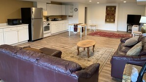 Un salon moderne avec un canapé en cuir, une table basse en bois et un téléviseur.