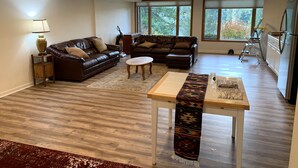 Un salon spacieux avec deux canapés en cuir, une table basse en bois et un tapis à motifs.