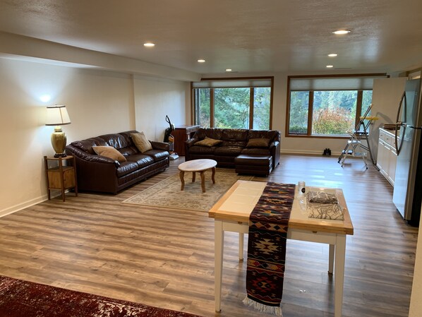 A spacious living room with two leather sofas, a wooden coffee table, and a patterned rug.