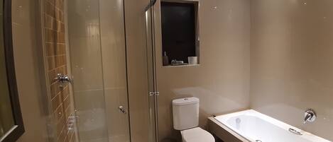Un baño moderno con cabina de ducha de vidrio, inodoro y bañera.