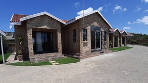 A modern two-story house with a brick exterior, large windows, and a paved driveway. - Citystay Ladybrand (Mantsopa)