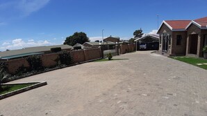A paved driveway leading to a building with a brick facade and a red roof. - Citystay Ladybrand (Mantsopa)