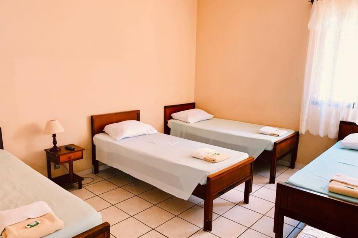 A hotel room with two single beds, a small bedside table with a lamp, and a desk with a chair.