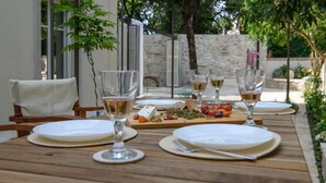 An outdoor dining area with wooden tables, white plates, and wine glasses. - Carpofoli Corfu (Corfu)